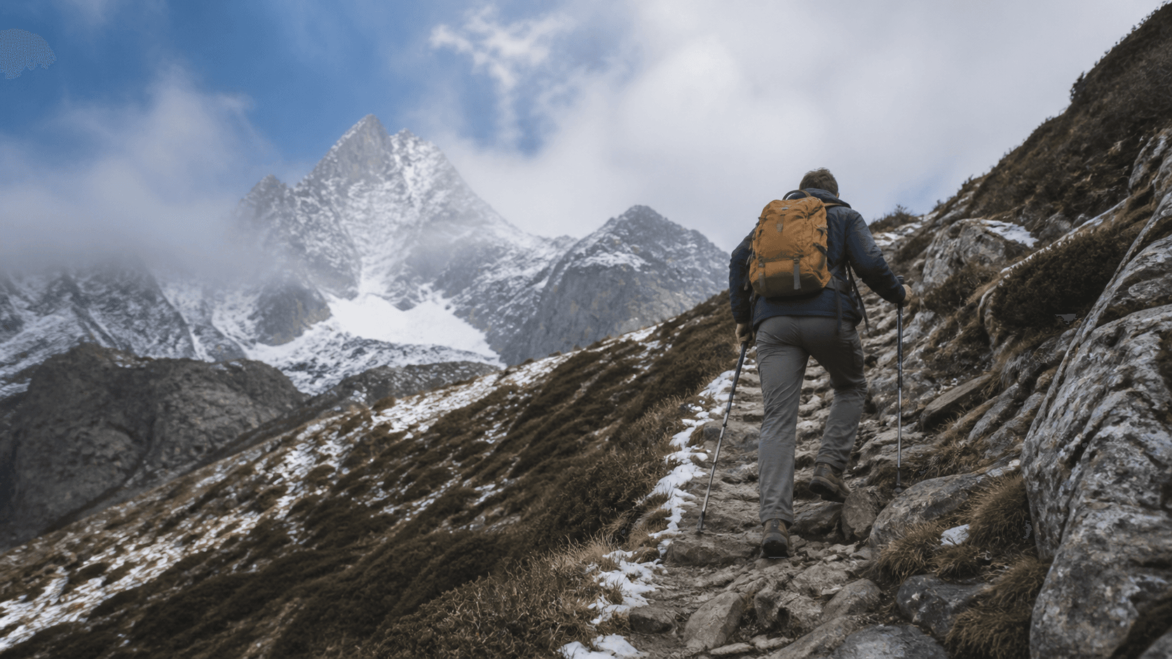 Persona ascendiendo por una pendiente rocosa hacia una cumbre nevada como símbolo de liderazgo y superación de desafíos